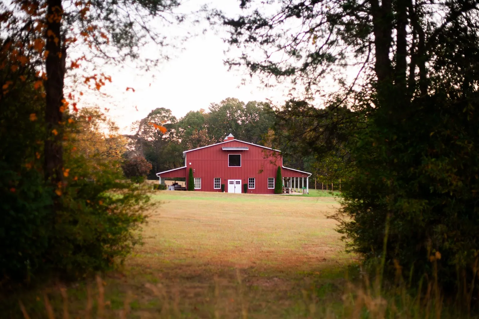 The red barn at The Heritage Barn across a golden autumn field on the 30-acre grounds near Hickory, NC