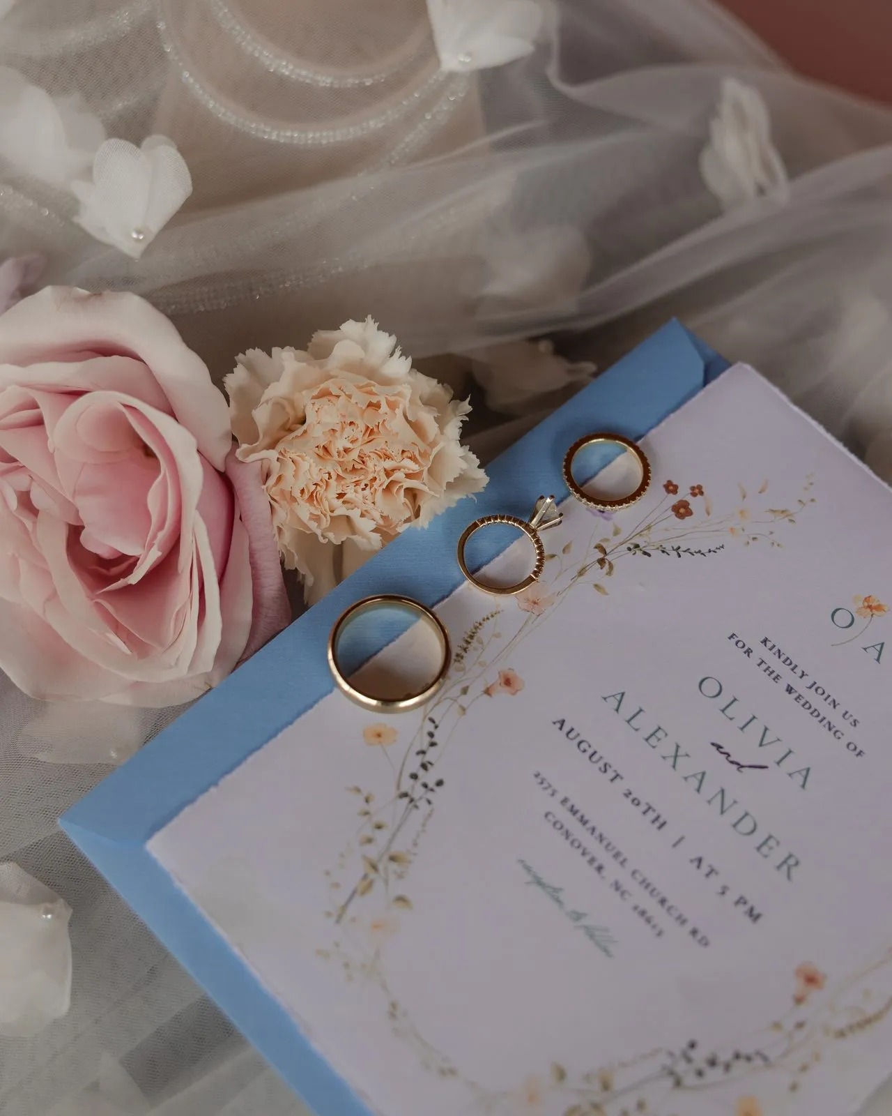 Wedding invitation and rings styled with garden roses at The Heritage Barn wedding venue